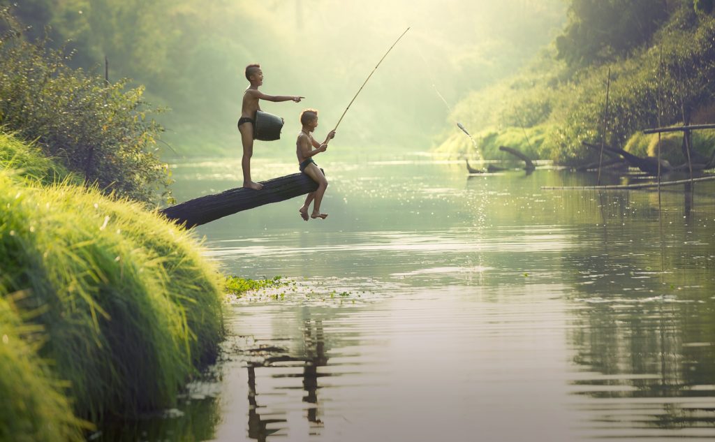 2drenge fisker med stang ved idyllisk flod